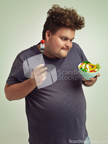 Image of Happy, plus size and man with salad in studio for healthy diet, natural nutrition and weight loss. Male person, organic food and tomato on fork with thinking for vitamin c, detox or vegan change
