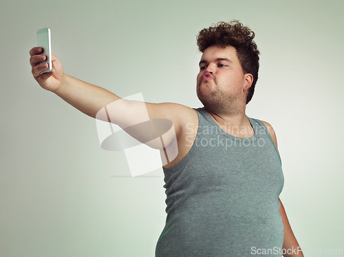 Image of Selfie, phone and plus size man in studio posing with casual, trendy and cool outfit with stomach. Cellphone, pout and overweight male person with photography picture isolated by gray background.