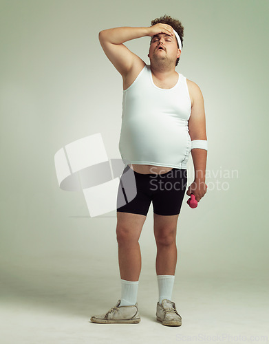 Image of Plus size, tired man and dumbbells for exercise, training or workout in studio isolated on a white background mockup space. Body, fatigue and person on break with weights for muscle, fitness or rest