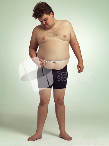 Image of Man, plus size and stomach with measurement in studio on white background with tape for progress, weight loss and exercise. Positivity, fitness and body with self care to monitor health and shape