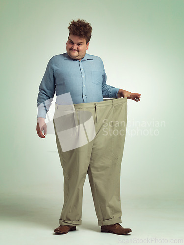 Image of Happy man, portrait and plus size with pants for weight loss, measurement or waist on a studio background. Male person with smile for healthy diet, obesity or overweight clothing on mockup space