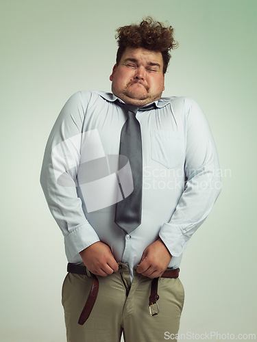 Image of Man, pants and plus size with big waist in obesity, overweigh or measurement on a studio background. Young male person struggling to fit on clothing with body fat or chubby stomach on mockup space