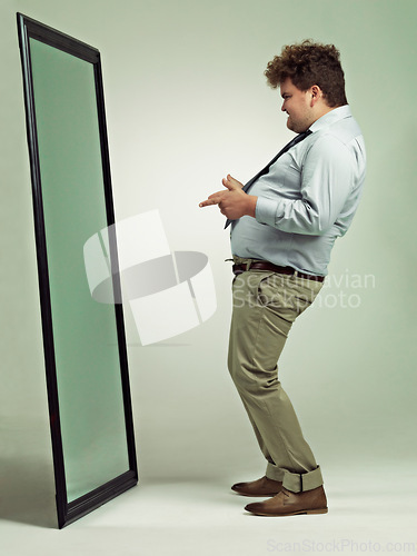 Image of Man, mirror and plus size with reflection for confidence in body fat, fashion or outfit on a studio background. Young male person or big model in obesity, overweight or challenge on mockup space