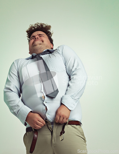 Image of Frustrated man, pants and plus size with big waist in obesity or overweight on a studio background. Young male person struggling to fit on clothing with body fat or chubby stomach on mockup space