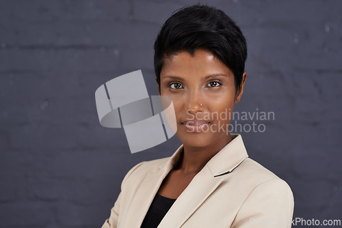 Image of Indian woman, serious in portrait and corporate professional, pride and ambition with confidence on wall background. Business headshot, assertive face and real estate agent in Mumbai with mission