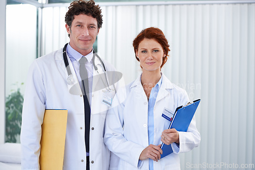 Image of Doctors, man and woman with smile in portrait for team, partnership and documents with pride for healthcare. Medic employees, people and clipboard in clinic for collaboration, wellness and services