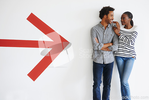 Image of Couple, love and happiness with arrow by wall in car park with mockup space and romance with smile. African people, embrace and arms crossed in parking area with direction, sign and symbol of icon