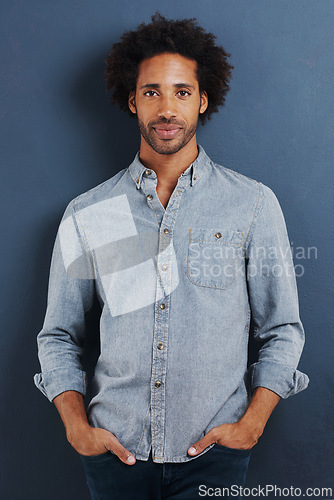 Image of Black man, portrait and casual for fashion with denim shirt, calm and cool in studio with afro on blue background. African model with smile, pride and pose with hands in pocket and stylish clothes