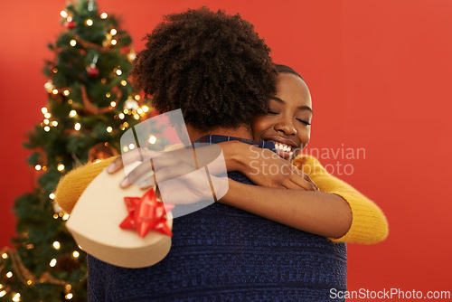 Image of Christmas, present and black couple in hug with box or opening surprise on festive holiday or vacation with happiness. Embrace, woman and man offer a gift in home with love and kindness in marriage