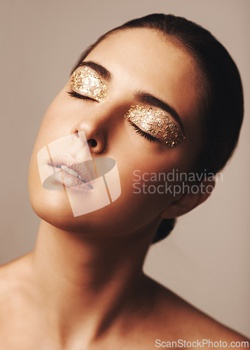 Image of Woman, face and gold glitter eyeshadow for beauty, cosmetology and glamour with cosmetics on beige background. Makeup, elegance and fashion model in studio, art or creativity with shimmer and glow