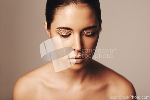 Image of Woman, makeup and gold glitter on eyes for beauty, cosmetology and glamour with cosmetics on beige background. Eyeshadow, elegance and face model in studio, art or creativity with shimmer and glow