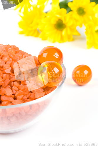 Image of bath salt, oil balls in a bowl and yellow flowers