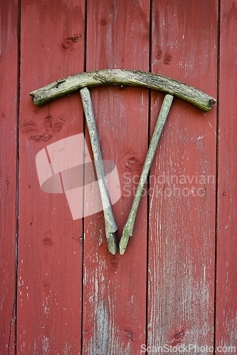 Image of part of a wooden cart wheel on a red wooden wall 