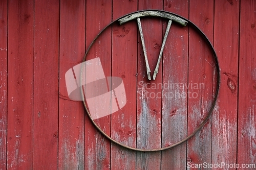 Image of part of a wooden cart wheel on a red wooden wall 