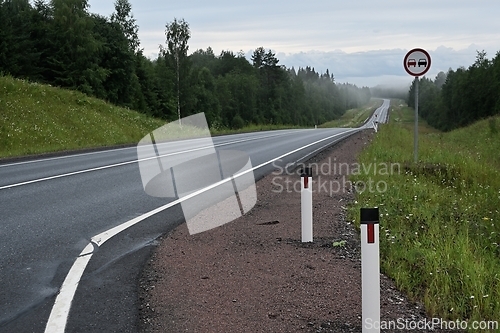 Image of suburban road with one car and no overtaking sign