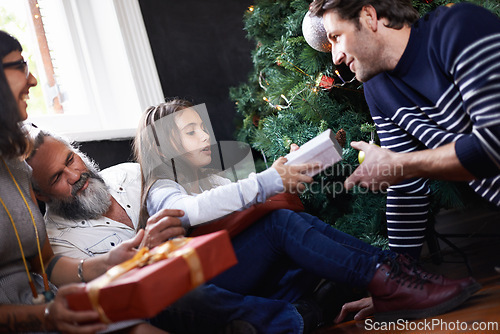 Image of Father, child and gift by Christmas tree in home, festive season and present for bonding on xmas. Happy family, girl and happy for package on religious holiday, celebration and love for tradition