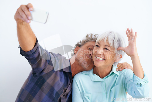 Image of Old couple, kiss in selfie and happy together for social media post, memory and love with fun on white background. Affection, trust or loyalty with people in marriage, smile in picture and mobile app