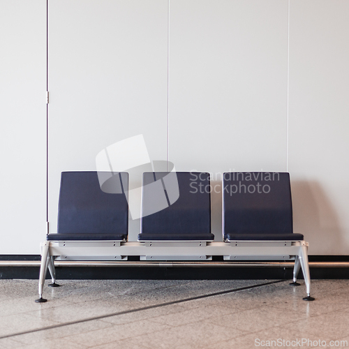 Image of Rectangular chairs lined up against white wall in waiting room