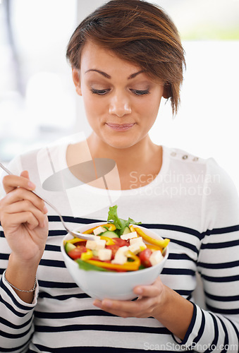 Image of Young woman, diet and salad or healthy food for detox, breakfast and lunch at home. A happy person with green fruits, vegetables and eating lettuce or vegan meal in bowl for nutrition and wellness