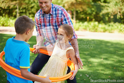 Image of Father, kids and hula hoop in park for playing, child development and motor skills outdoor. Children, son and daughter with dad in nature for leisure, family time and bonding with smile on grass