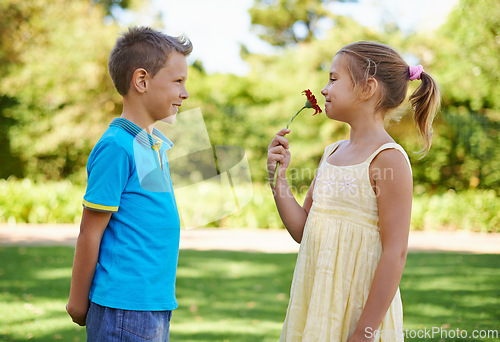 Image of Children, friends and flower gift or outdoor connection with love kindness or young care, bonding or innocent. Boy, girl and smile at backyard garden for smell plant or summer holiday, play or park