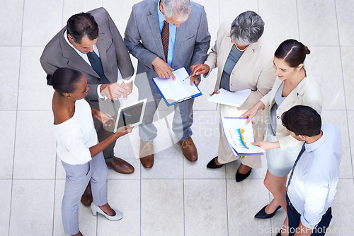 Image of Documents, tablet and business people in meeting in lobby of office in collaboration. Paperwork, digital technology and high angle of professional financial advisors in discussion for teamwork.