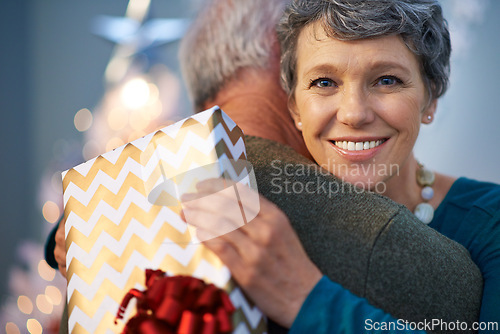Image of Christmas, gift and senior couple with love, hug and gratitude for holiday surprise, celebration and tradition at night. Portrait of elderly woman by bokeh lights with present pr thanksgiving at home