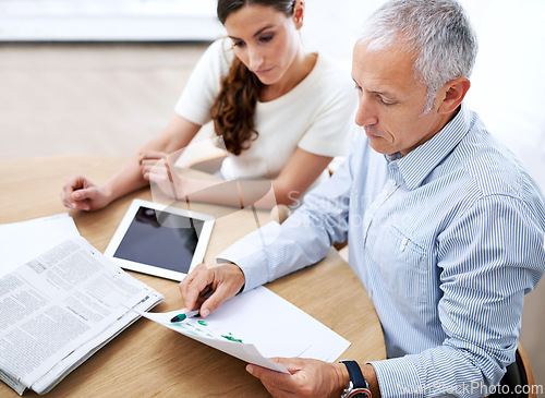 Image of Meeting, man and woman in office with paperwork for sales review, stats growth or development. Planning, strategy and business people at desk with tablet, newspaper and data analysis on profit trends