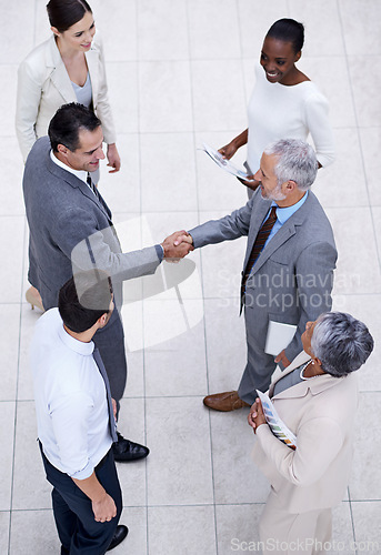 Image of Team, handshake and happy business people with CEO for deal, collaboration or partnership agreement for diverse financial advisors. Top view, shaking hands and group in office meeting for acquisition