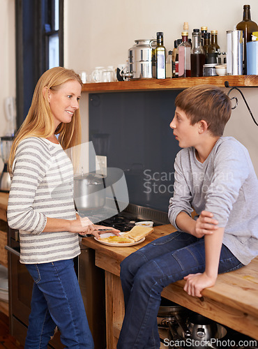 Image of Mother, child and cooking food in kitchen for morning breakfast on counter for toast meal, brunch or snack. Woman, son and conversation in home for healthy nutrition or hungry, wellness or together