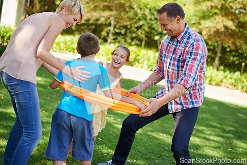 Image of Parents, children and hula hoop in park as family, playing and bonding with motor skills outdoor. Kids, son and daughter with mother and father in nature for leisure, childhood development with smile