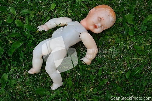 Image of old broken doll on a grass