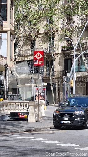 Image of BARCELONA, SPAIN - APRILL 4, 2024: Black taxi car driving along tall buildings