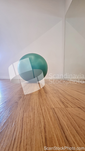 Image of Green exercise ball on wooden floor in modern interior