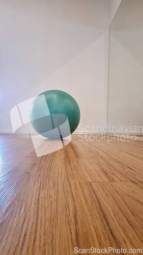 Image of Green exercise ball on wooden floor in modern interior