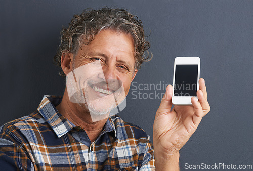 Image of Man, portrait and cellphone screen in studio for website communication, grey background or connectivity. Male person, face and smile with smartphone for online internet, advertising or mockup space