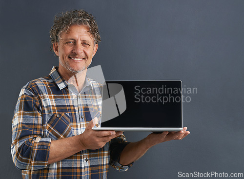 Image of Laptop, screen and portrait of mature man in studio and learning about technology on dark background. Advertising, computer and mockup with online post to social media and search internet for news