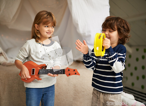 Image of Music, playing and children with instruments in bedroom for fun, bonding and band practice. Happy, smile and young girl and boy kids with guitar and tambourine toys enjoying musical song at home.