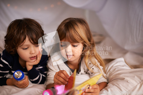 Image of Reading, blanket fort and children with book for knowledge, learning and education with flashlight. Bonding, relaxing and young kids enjoying story or novel together in tent for sleepover at home.