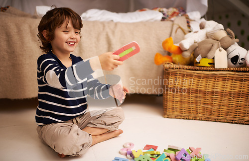 Image of Boy, child and happy with letter toys to learn, development and games in bedroom at home. Excited, education and growth in childhood with alphabet, language and kid playing for fun at family house