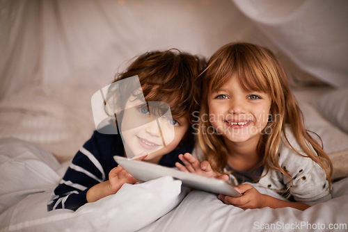 Image of Tablet, blanket fort and portrait of kids relaxing, bonding and playing together at home. Happy, smile and young girl and boy children siblings laying in tent for fun sleepover in bedroom at house.