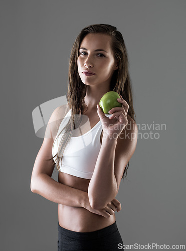 Image of Portrait, apple and woman with nutrition, fitness and wellness on a grey studio background. Face, person and model with fruit and gut health with diet plan and balance with benefits and digestion