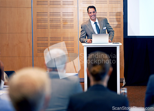 Image of Businessman, presentation and conference with laptop for team meeting, staff training or seminar at the office. Man, employee or speaker talking with smile on podium for company or business workshop