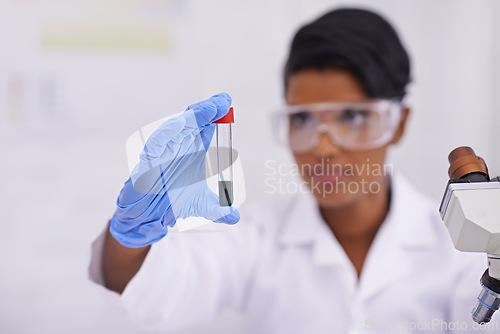 Image of Blood, hand and scientist with test tube in laboratory for scientific research or experiment. Microscope, science and woman researcher with pharmaceutical dna in glass vial for medical study.