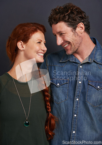 Image of Love, smile and happy couple in studio together with relationship trust, care and support. Romance, casual man and woman embrace on dark background with commitment, loyalty and affection in marriage