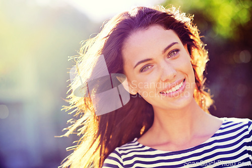 Image of Woman, portrait and smile with nature, sunrise and park for happiness and wellness. Person, joy and bokeh with closeup, glow and sunshine for summer relax and adventure outside in garden with trees