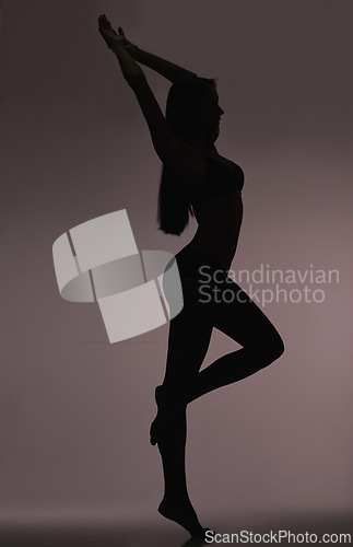 Image of Slim girl, woman and silhouette with beauty, body care and sensual on a dark studio background. Person, profile and model with shadow figure and seductive with stretching and natural pose with dancer