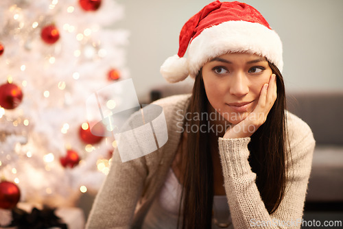 Image of Christmas, face and thinking with bored woman in living room of home for memory or nostalgia. Planning, idea or sad and lonely young person with Santa hat in apartment for December holiday season