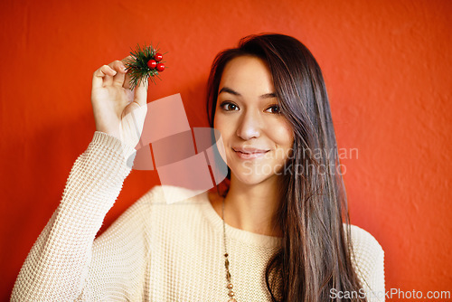 Image of Christmas, portrait and happy woman with holly branch in hand and winter celebration by red background. Young, person and smile on face with holiday decoration, gift and symbol of peace or goodwill