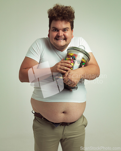Image of Candy, crazy and portrait of plus size man on white background for snacks, sweets and dessert in container. Comic, funny and isolated person with glass jar for unhealthy diet and sugar in studio
